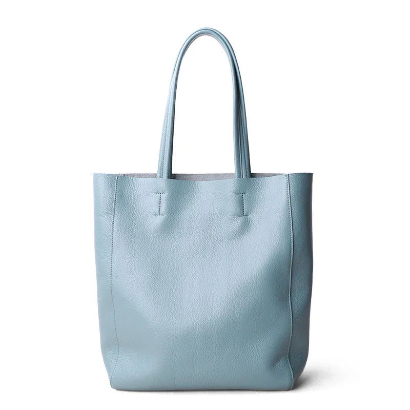 Minimalist light blue leather tote bag with double handles, ideal for everyday use or work.