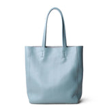 Minimalist light blue leather tote bag with double handles, ideal for everyday use or work.