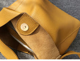 Minimalist yellow pebbled cowhide leather bucket bag with wide shoulder strap and snap closure