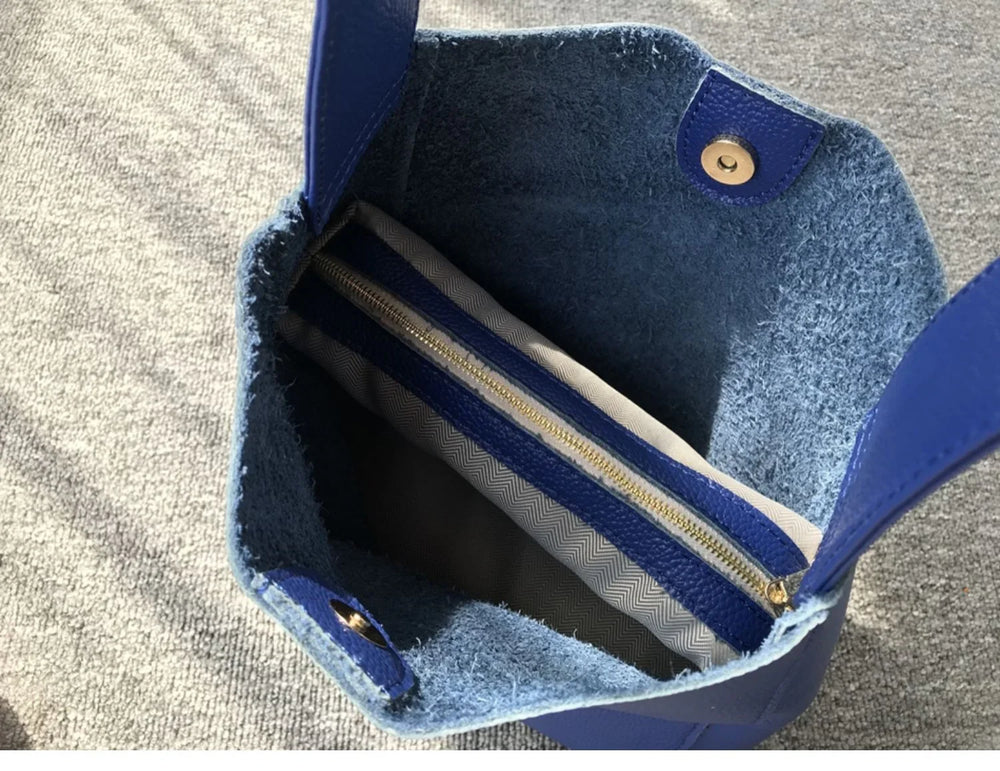 Interior view of minimalist blue pebbled leather bucket bag with wide strap and zipper pouch