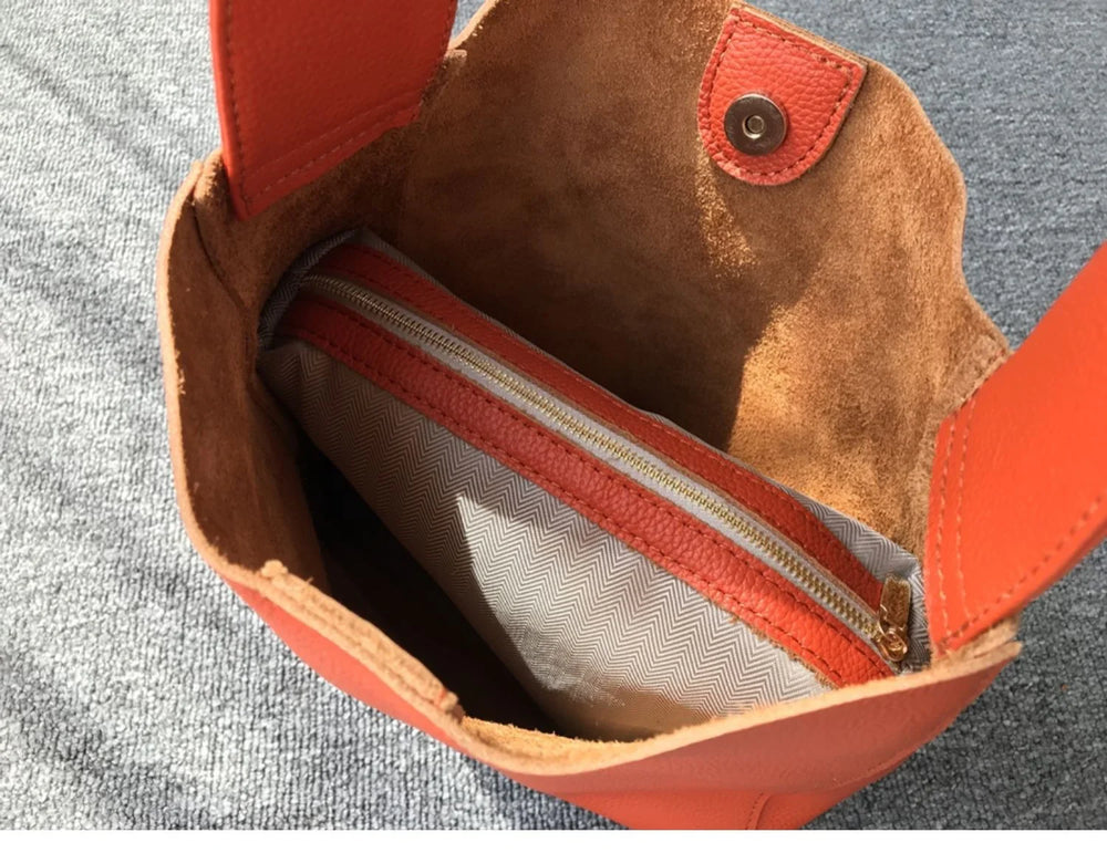 Inside view of an orange pebbled leather bucket bag with a wide strap and inner zip pouch