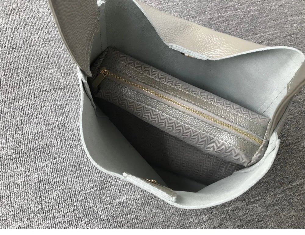 Open minimalist pebbled cowhide leather bucket bag with wide shoulder strap and zip pouch