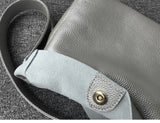 Minimalist pebbled cowhide leather bucket bag with wide shoulder strap in grey