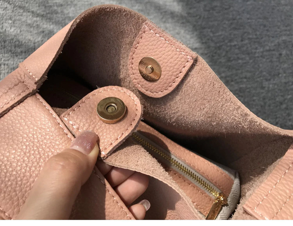 Close-up of pink pebbled cowhide leather bucket bag with snap closure and zippered pocket