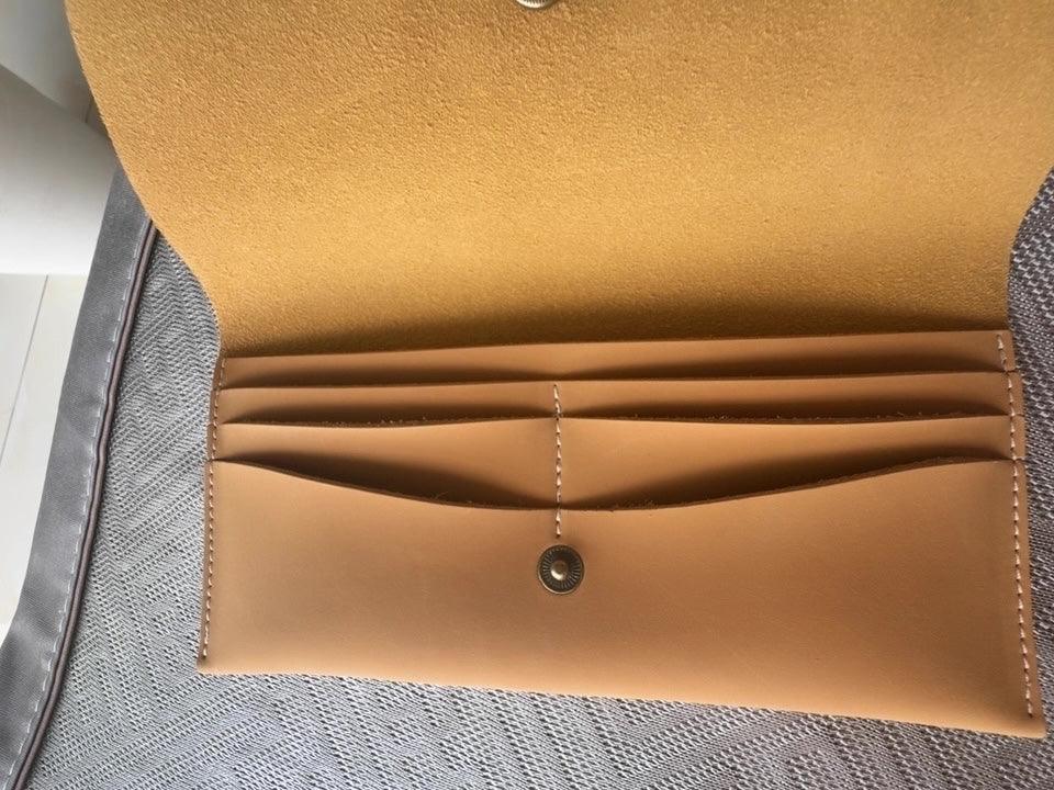 Tan leather wallet with multiple card slots and snap button closure on a fabric surface