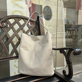 Handcrafted soft beige leather tote bag with two front pockets on a bench outdoors
