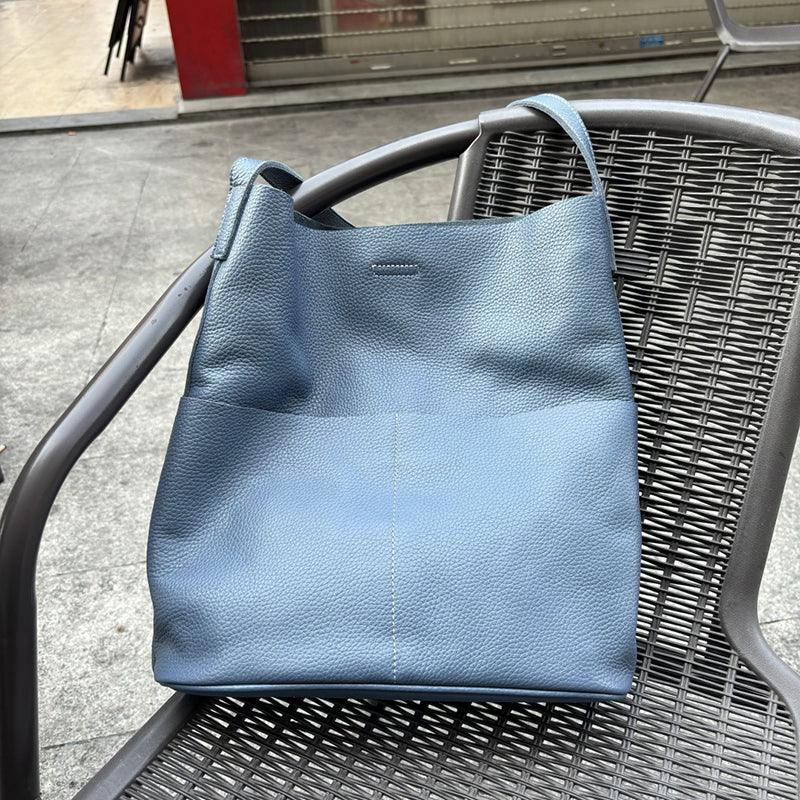 Blue cowhide leather tote bag with two front pockets on outdoor chair