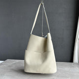 Cream cowhide leather tote bag with two front pockets, minimalist design, on marble surface