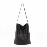 Black cowhide leather tote bag with two front pockets and long shoulder strap on white background