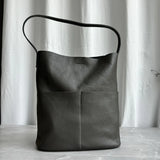 Soft dark brown cowhide leather tote bag with two front pockets and a single shoulder strap, displayed upright.