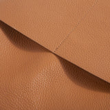 Closeup of soft tan cowhide leather with detailed stitching on a tote bag pocket