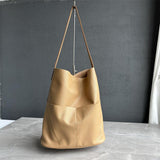 Tan cowhide leather tote bag with two front pockets on a grey background