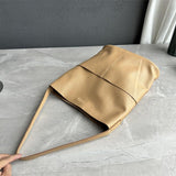 Tan cowhide leather tote bag with two front pockets on marble surface