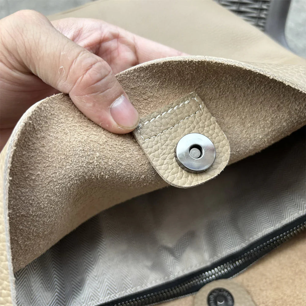 Closeup of tan cowhide leather tote bag with snap closure and zipper pocket