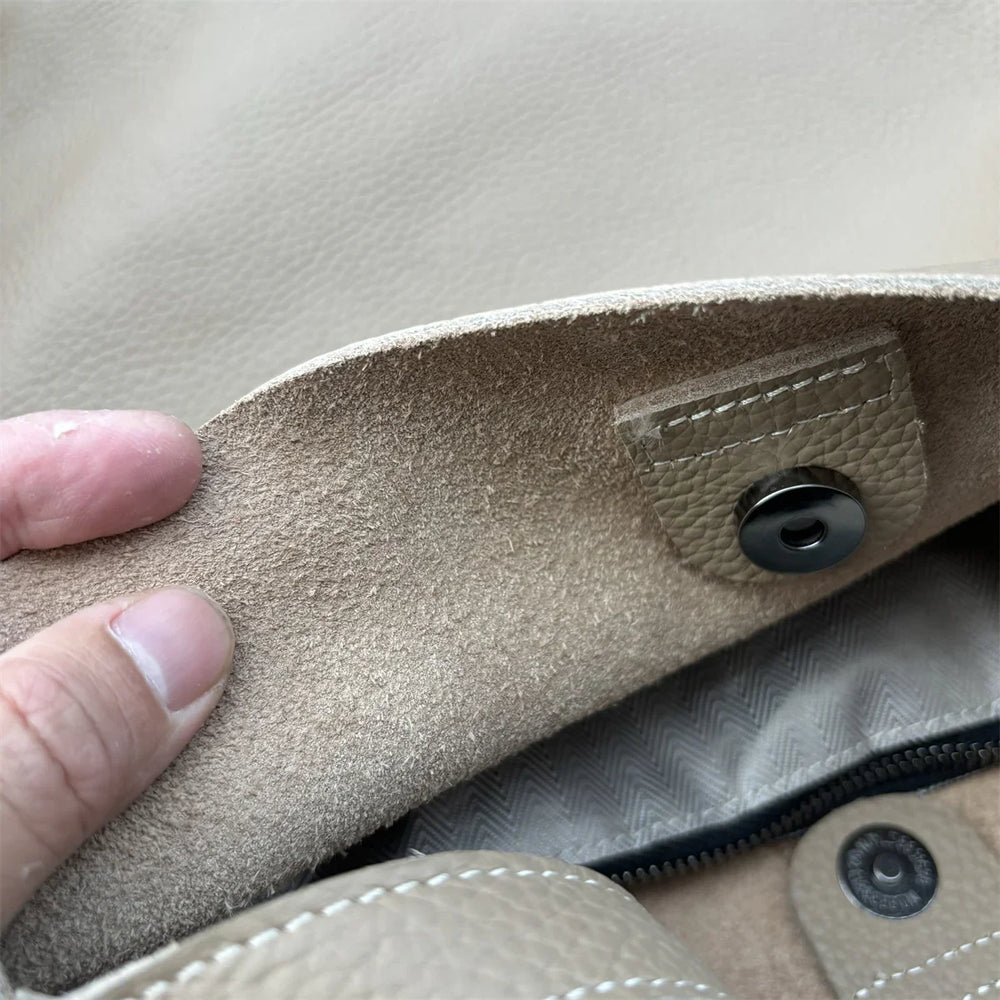 Close-up of beige cowhide leather tote bag interior with snap button and stitched detail