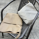 Soft beige cowhide leather tote bag with two front pockets on a chair, minimalist style