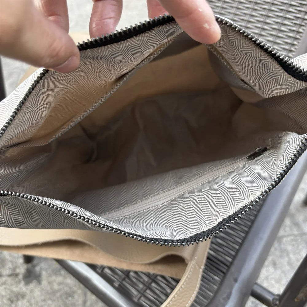Interior view of beige leather tote bag showing zippered pocket and patterned lining