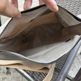 Interior view of beige leather tote bag showing zippered pocket and patterned lining