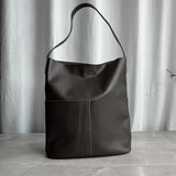 Minimalist dark brown cowhide leather tote bag with two front pockets and single shoulder strap