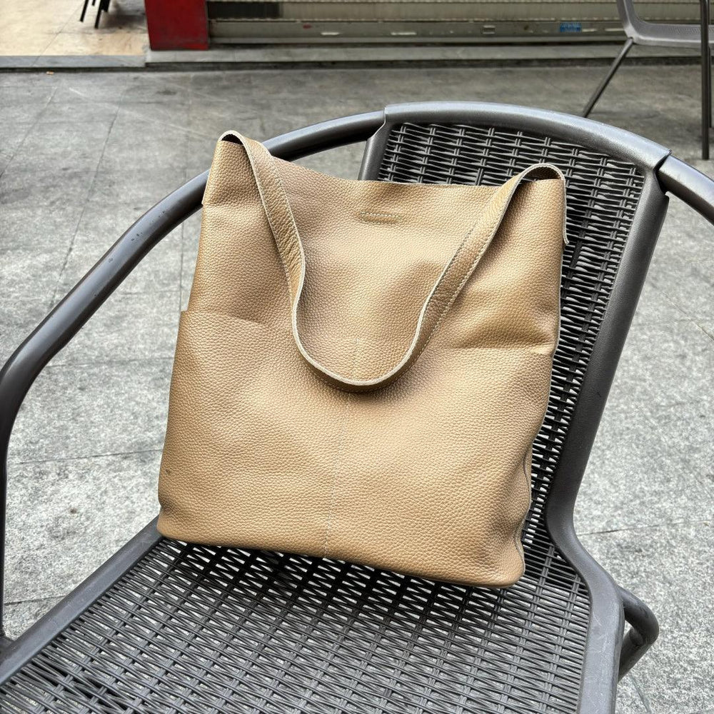 Beige cowhide leather tote bag with soft texture on a black outdoor chair
