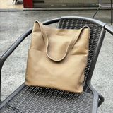 Beige cowhide leather tote bag with soft texture on a black outdoor chair