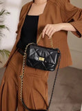 Woman holding black quilted leather shoulder bag with gold chain strap and gold lock clasp