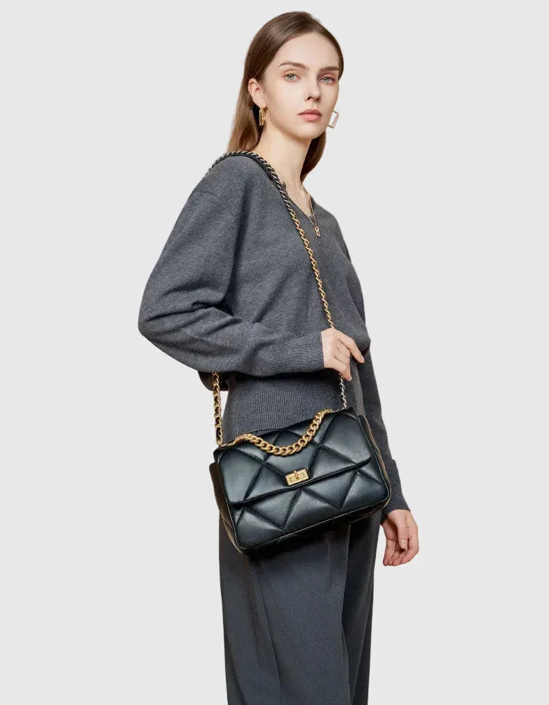 Woman with black quilted leather shoulder bag featuring gold chain strap and turn-lock clasp