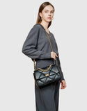 Woman with black quilted leather shoulder bag featuring gold chain strap and turn-lock clasp