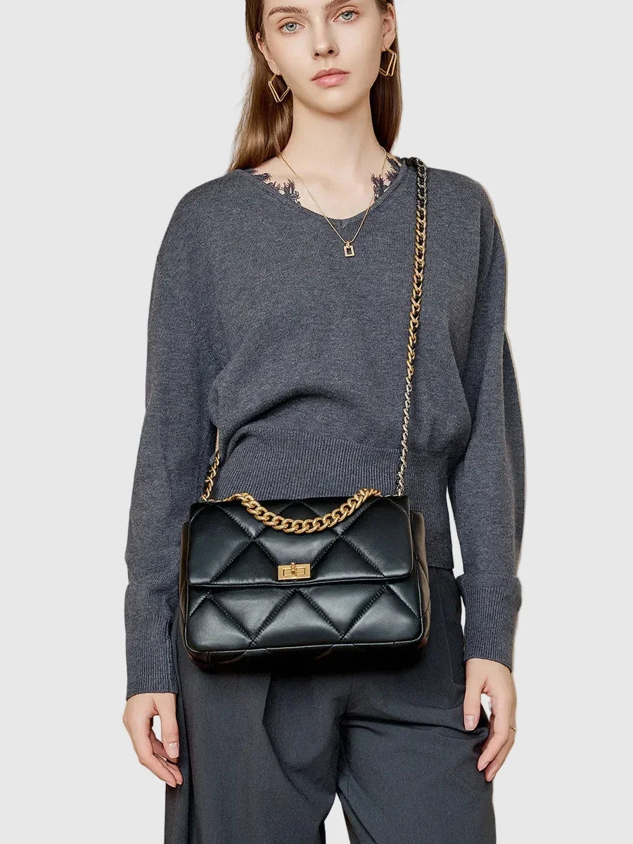 Woman wearing black quilted genuine leather shoulder bag with gold chain strap and lock