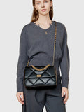 Woman wearing black quilted genuine leather shoulder bag with gold chain strap and lock