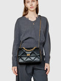 Woman wearing black quilted genuine leather shoulder bag with gold chain strap and lock