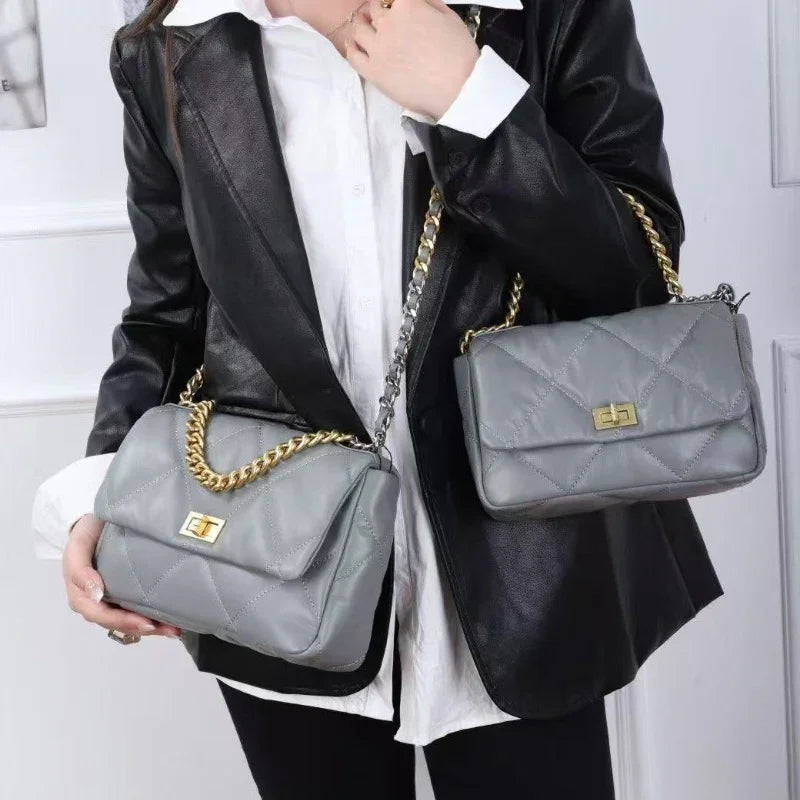 Woman in black blazer holding two grey quilted genuine leather shoulder bags with gold chains