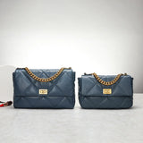 Two quilted blue leather flap bags with gold chain straps and gold turn-lock closures on a gray surface