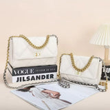 Quilted white leather shoulder bags with gold chain straps and turn-lock closures, styled on books and magazines