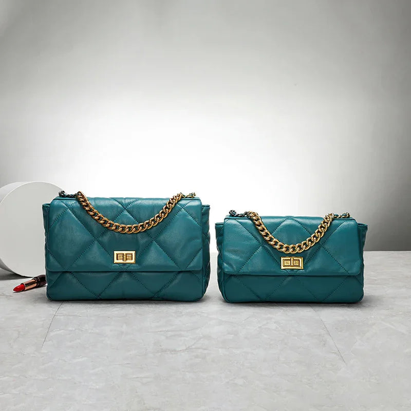 Teal quilted leather shoulder bags with gold chain strap and clasp on marble surface
