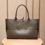 Quilted large leather tote bag with top handles, minimalist design on wooden table