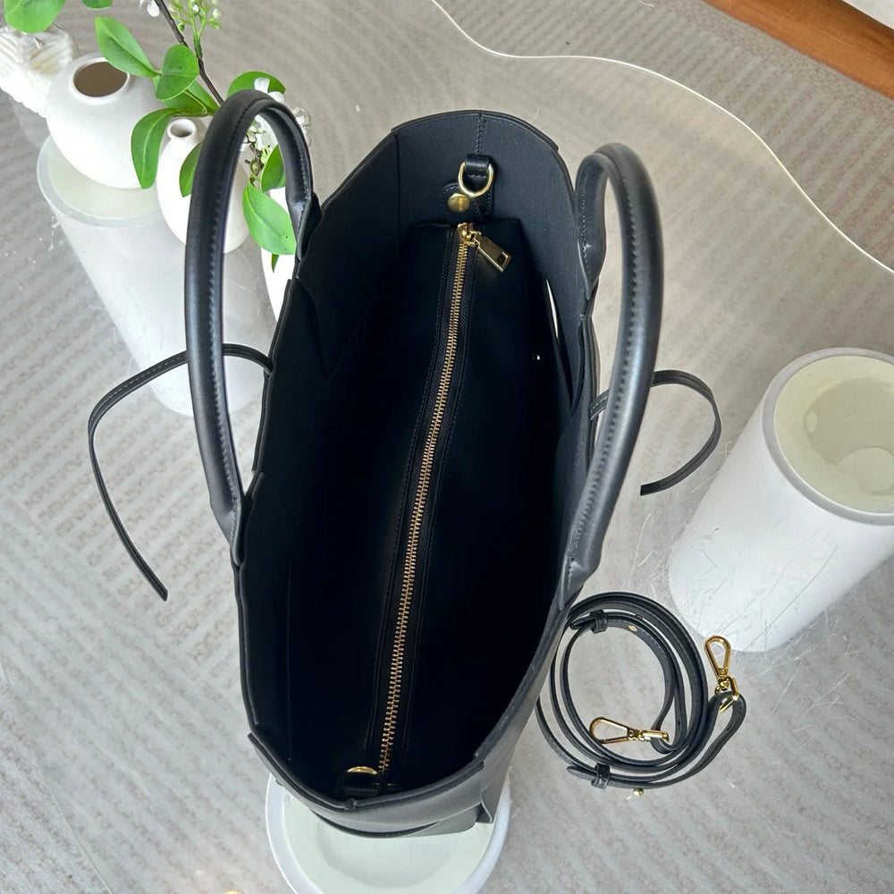 Interior view of large black leather tote bag with gold zipper pocket and detachable strap