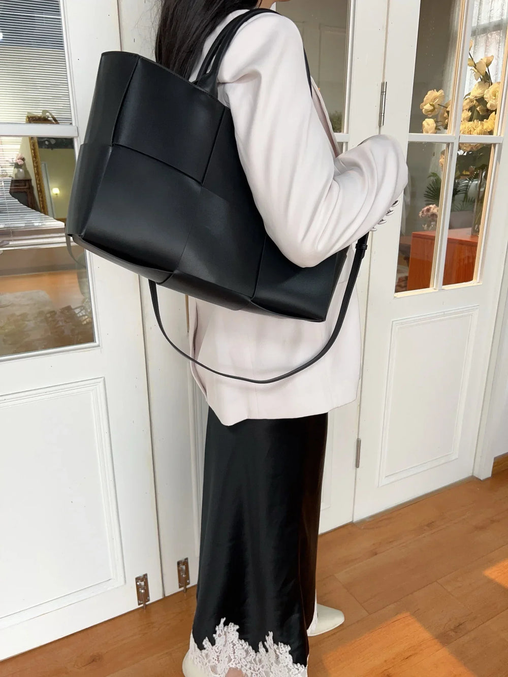 Woman wearing a black quilted leather tote bag with top handles and minimalist style