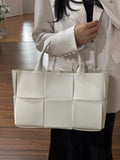 Woman holding a large white quilted leather tote bag with top handles, minimalist style