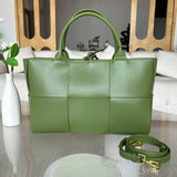 Green quilted leather tote bag with top handles and detachable shoulder strap on a table