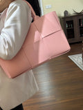 Woman carrying a large pink quilted leather tote bag with top handles, minimalist style