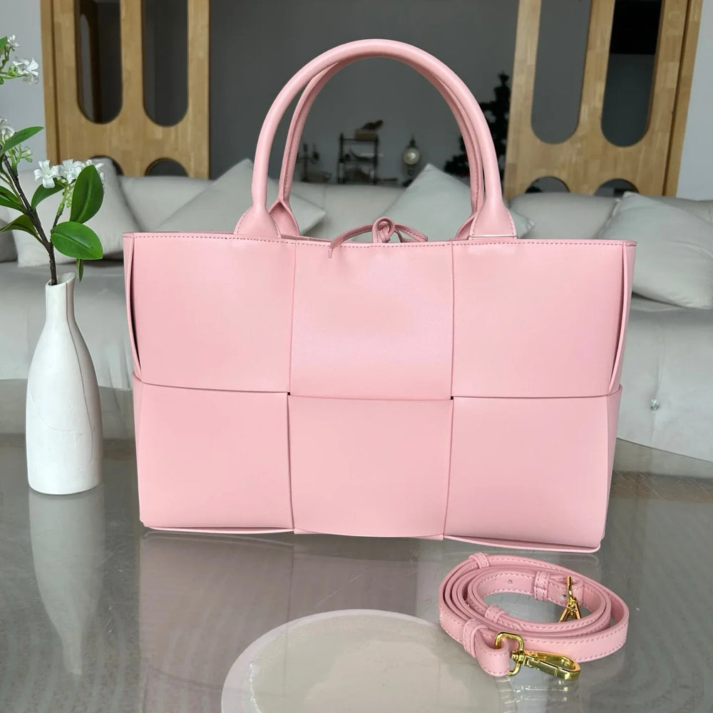 Large pink quilted leather tote bag with top handles and detachable shoulder strap on table