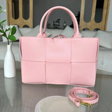 Large pink quilted leather tote bag with top handles and detachable shoulder strap on table