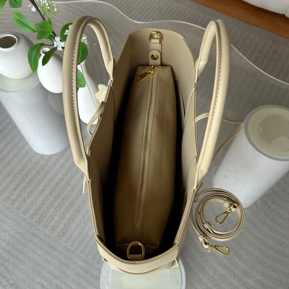 Top view of a beige leather tote bag with gold hardware, zippered pouch, and adjustable strap.