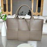 Taupe quilted large leather tote bag with top handles on a glass table, minimalist interior
