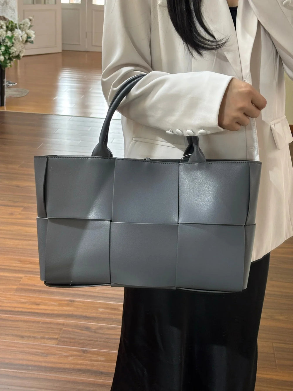 Woman holding a large quilted leather tote bag with top handles, minimalist and elegant style
