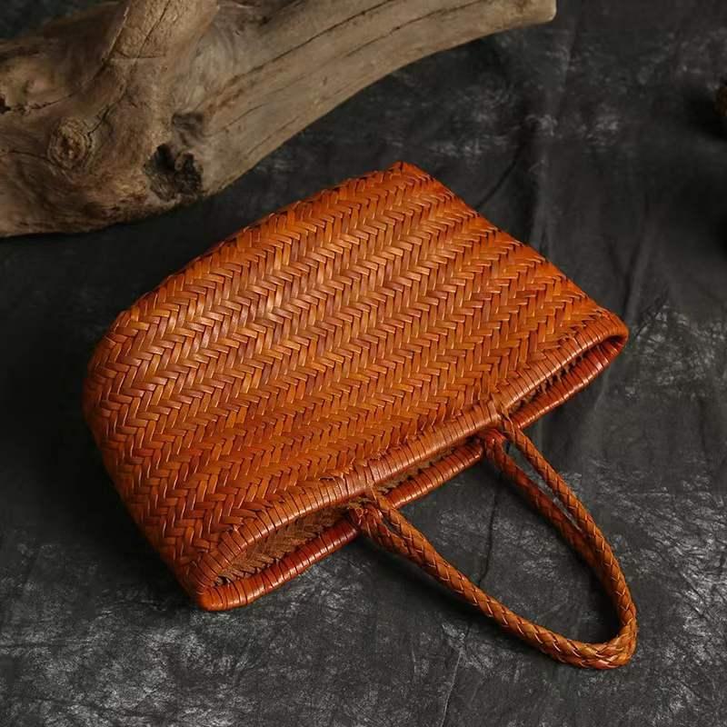 Handmade woven Italian leather tote bag with dual handles on dark textured surface