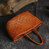 Handmade woven Italian leather tote bag with dual handles on dark textured surface