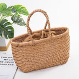Handmade woven leather tote bag in tan with braided handles on white surface