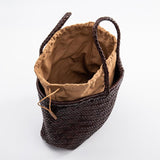 Dark brown woven leather tote bag with tan fabric lining and handles on white background